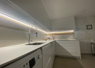 Cocina DiGiovanni, Reforma, Zaragoza, cocina, Mueble a medida, cocina moderna, cocina blanca, blanco y marmol, taburete alto, barra, mesa alta, Porcelanosa, tirador oculto, amueblamiento, Silestone, Dekton, Consentino, encimera crema, campana oculta, barra desayuno, Balay, Bosch, cemento, reloj cocina, mueble auxiliar, electrodomesticos negros,, horno cristal negro, microondas cristal negro, frigorifico acero, cocina, suelo crema, decorativo, cocina alargada, baldosa blanca, mueble microondas, taburete rojo, cocina azul, turquesa, mueble caldera, decorativo, encimera granito negro, tira led, luz led, mueble blanco, electrodomésticos cristal blanco, encimera marmol blanco, frontal blanco y madera, papel pintado