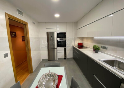 Cocina DiGiovanni, Reforma, Zaragoza, cocina, Mueble a medida, cocina moderna, cocina blanca, taburete alto, barra, mesa cocina, Porcelanosa, tirador oculto, amueblamiento, Silestone, Dekton, Consentino, encimera marmol blanco, campana oculta, barra desayuno, Balay, Bosch, cemento, reloj cocina, mueble auxiliar, electrodomesticos blancos, horno cristal blanco, microondas cristal blanco, frigorifico acero, cocina, suelo crema, decorativo, cocina alargada, baldosa blanca, mueble microondas, decorativo, tira led, luz led, mueble blanco, frontal blanco y madera, mueble madera y blanco, campana integrada, encimera granito importacion, granito negro, mueble madera, electrodomesticos cristal gris, mueble blanco, campana decorativa blanca, microondas en alto, vitrinas, vinoteca