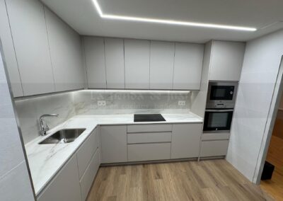 Cocina DiGiovanni, Reforma, Zaragoza, cocina, Mueble a medida, cocina moderna, cocina blanca y negra, taburete madera, Porcelanosa, Saloni, tirador oculto negro, amueblamiento, Silestone, Dekton, Consentino, encimera negra, campana decorativa cristal negro, Balay, Bosch, reloj cocina, mueble auxiliar, electrodomesticos negros, horno cristal negro, microondas cristal negro, frigorifico acero, cocina, suelo gris, decorativo, cocina alargada, baldosa blanca, mueble microondas, decorativo, tira led, luz led, mueble blanco, frontal, mueble madera y blanco, mueble blanco, electrodomesticos acero, mueble blanco, campana decorativa negra, columna horno microondas, frigorífico cajones, pared pizarra