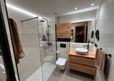 Aseo, Baño DiGiovanni, Reforma, Zaragoza, Baño, Mueble a medida, amueblamiento, mueble blanco, lavabo sobre encimera, tirador oculto, mueble cajones, durian, corian, krion, encimera madera, mampara cristal, cerámica mosaico, cerámica crema, cerámica lineas, suelo gris, radiador toallero, columna ducha, plato ducha pizarra, plato ducha a ras, toallero en alto, mampara de dos hojas, bañera, espejo luz led, mampara bañera
