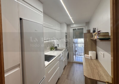 Cocina DiGiovanni, Reforma, Zaragoza, cocina, Mueble a medida, cocina moderna, cocina blanca y negra, taburete madera, Porcelanosa, Saloni, tirador oculto negro, amueblamiento, Silestone, Dekton, Consentino, encimera negra, campana decorativa cristal negro, Balay, Bosch, reloj cocina, mueble auxiliar, electrodomesticos negros, horno cristal negro, microondas cristal negro, frigorifico acero, cocina, suelo gris, decorativo, cocina alargada, baldosa blanca, mueble microondas, decorativo, tira led, luz led, mueble blanco, frontal, mueble madera y blanco, mueble blanco, electrodomesticos acero, mueble blanco, campana decorativa negra, columna horno microondas, frigorífico cajones, pared pizarra, mueble azul mate