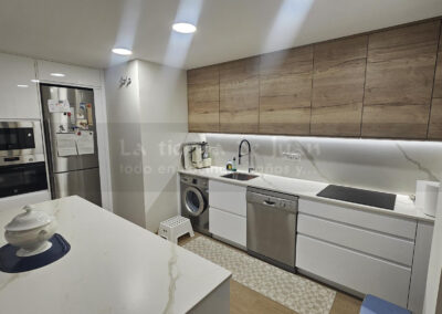 Cocina DiGiovanni, Reforma, Zaragoza, cocina, Mueble a medida, cocina moderna, cocina blanca y negra, taburete madera, Porcelanosa, Saloni, tirador oculto negro, amueblamiento, Silestone, Dekton, Consentino, encimera negra, campana decorativa cristal negro, Balay, Bosch, reloj cocina, mueble auxiliar, electrodomesticos negros, horno cristal negro, microondas cristal negro, frigorifico acero, cocina, suelo gris, decorativo, cocina alargada, baldosa blanca, mueble microondas, decorativo, tira led, luz led, mueble blanco, frontal, mueble madera y blanco, mueble blanco, electrodomesticos acero, mueble blanco, campana decorativa negra, columna horno microondas, frigorífico cajones, pared pizarra, mueble azul mate