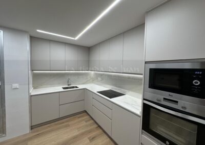 Cocina DiGiovanni, Reforma, Zaragoza, cocina, Mueble a medida, cocina moderna, cocina blanca y negra, taburete madera, Porcelanosa, Saloni, tirador oculto negro, amueblamiento, Silestone, Dekton, Consentino, encimera negra, campana decorativa cristal negro, Balay, Bosch, reloj cocina, mueble auxiliar, electrodomesticos negros, horno cristal negro, microondas cristal negro, frigorifico acero, cocina, suelo gris, decorativo, cocina alargada, baldosa blanca, mueble microondas, decorativo, tira led, luz led, mueble blanco, frontal, mueble madera y blanco, mueble blanco, electrodomesticos acero, mueble blanco, campana decorativa negra, columna horno microondas, frigorífico cajones, pared pizarra
