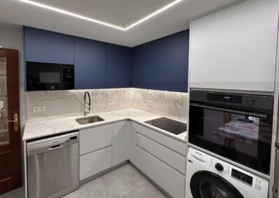 Cocina DiGiovanni, Reforma, Zaragoza, cocina, Mueble a medida, cocina moderna, cocina blanca y negra, taburete madera, Porcelanosa, Saloni, tirador oculto negro, amueblamiento, Silestone, Dekton, Consentino, encimera negra, campana decorativa cristal negro, Balay, Bosch, reloj cocina, mueble auxiliar, electrodomesticos negros, horno cristal negro, microondas cristal negro, frigorifico acero, cocina, suelo gris, decorativo, cocina alargada, baldosa blanca, mueble microondas, decorativo, tira led, luz led, mueble blanco, frontal, mueble madera y blanco, mueble blanco, electrodomesticos acero, mueble blanco, campana decorativa negra, columna horno microondas, frigorífico cajones, pared pizarra, mueble azul mate