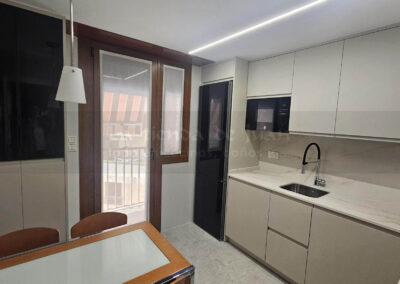 Cocina DiGiovanni, Reforma, Zaragoza, cocina, Mueble a medida, cocina moderna, cocina blanca y negra, taburete madera, Porcelanosa, Saloni, tirador oculto negro, amueblamiento, Silestone, Dekton, Consentino, encimera negra, campana decorativa cristal negro, Balay, Bosch, reloj cocina, mueble auxiliar, electrodomesticos negros, horno cristal negro, microondas cristal negro, frigorifico acero, cocina, suelo gris, decorativo, cocina alargada, baldosa blanca, mueble microondas, decorativo, tira led, luz led, mueble blanco, frontal, mueble madera y blanco, mueble blanco, electrodomesticos acero, mueble blanco, campana decorativa negra, columna horno microondas, frigorífico cajones, pared pizarra, mueble azul mate